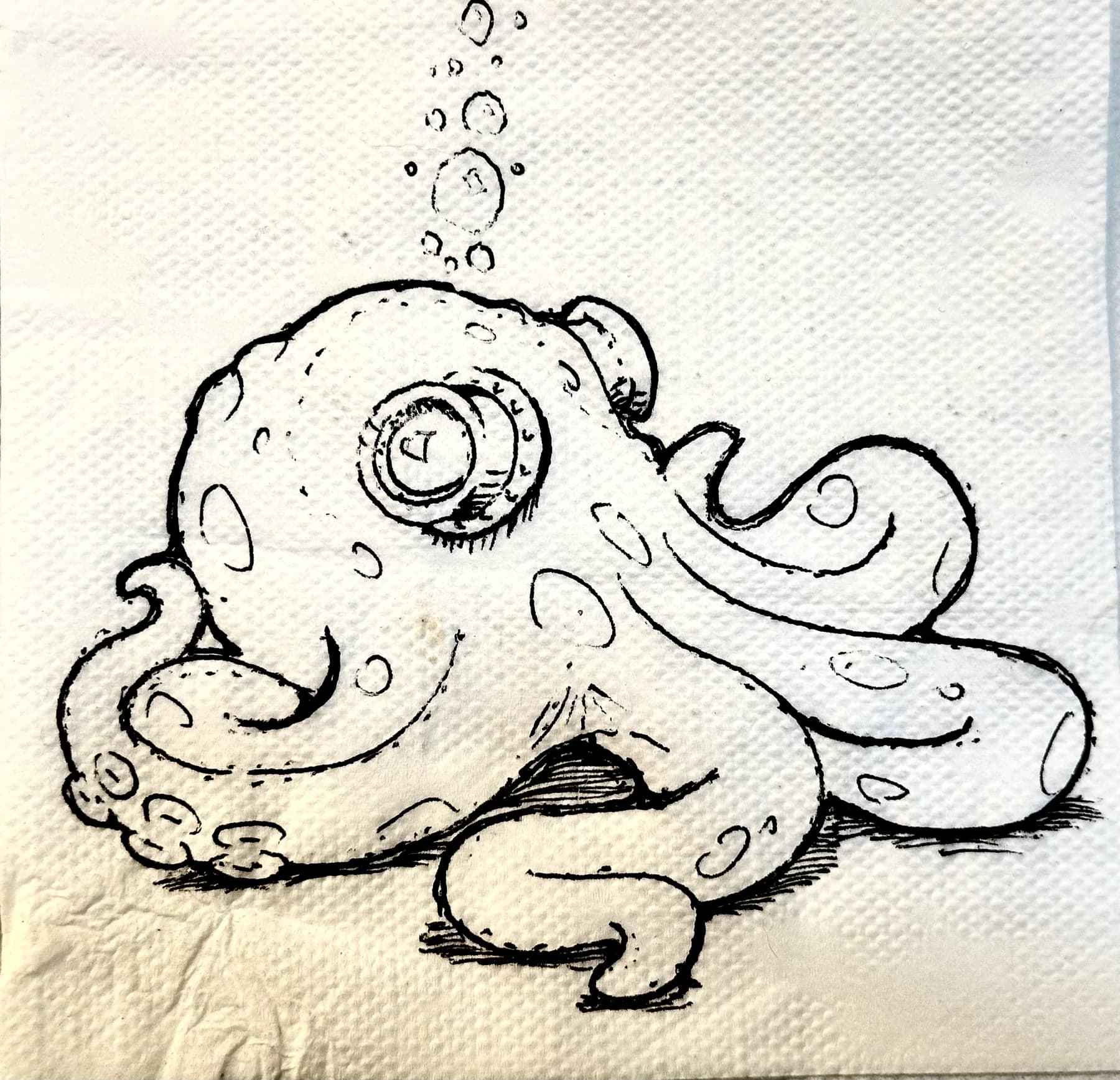 Ink drawing on a paper napkin of a spotted octopus with one large monocled eye, tentacles curling around itself, bubbles rising above.